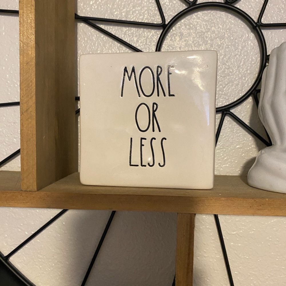 wall decor plaque is a Rae Dunn "Less Is More / More Or Less" ceramic block.